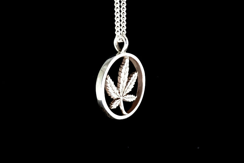 Silver pendant with a cannabis leaf design on a black background