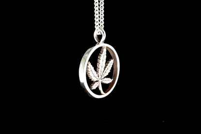 Silver pendant with a cannabis leaf design on a black background