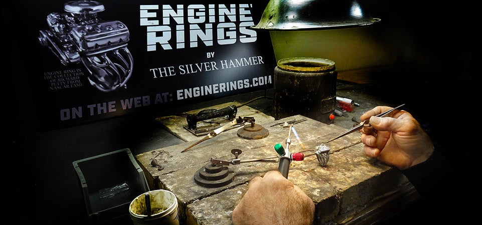 Person working on engine rings with tools on a workbench, promotional banner for 'Engine Rings by The Silver Hammer' in the background.