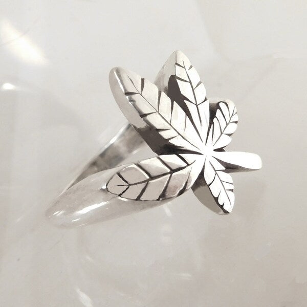 Silver leaf-shaped ring on a light gray background