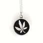 Necklace with a black pendant featuring a white leaf design on a white background